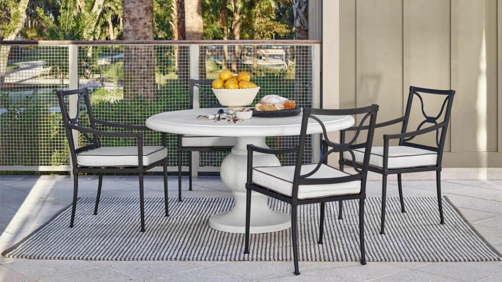 A white outdoor table and three metal chairs