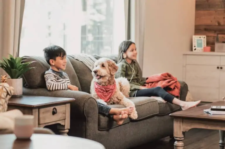 two happy kids and dog sitting on sofa in living room