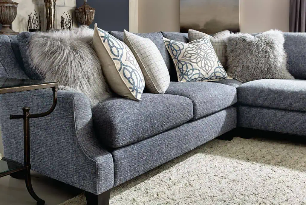 Gray sectional sofa with decorative pillows and faux fur throws.