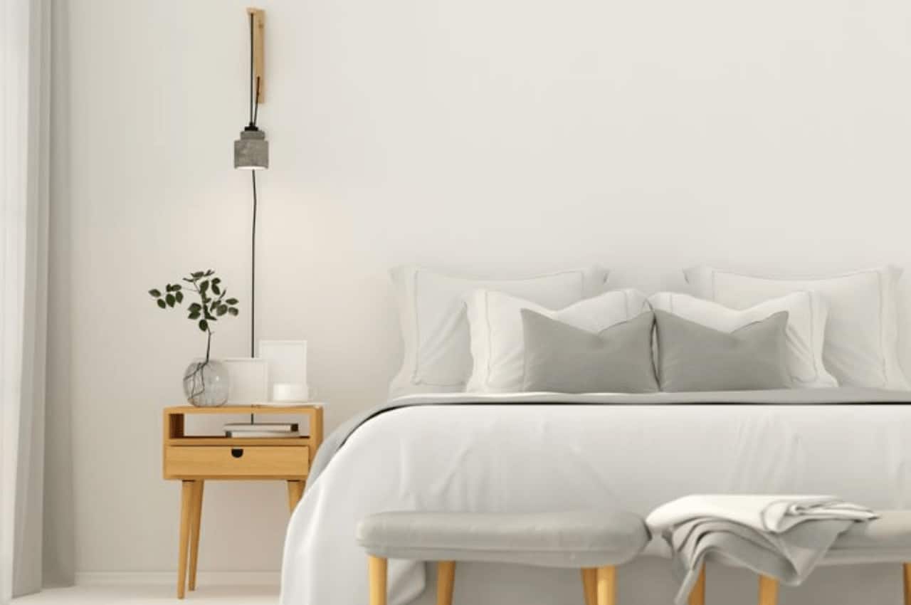 a nightstand sits next to a grey bed in a bedroom