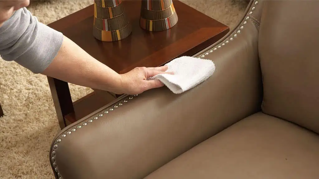 A person cleaning a leather chair from Bassett