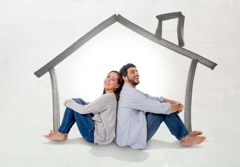 happy couple sitting back to back under house image