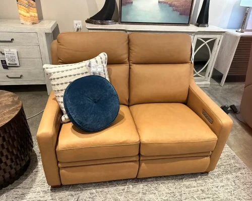 A tan leather recliner featuring a blue pillow, positioned for comfort in a cozy living space.