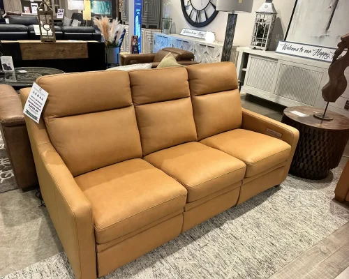 A tan leather sofa displayed in a furniture store, showcasing its sleek design and comfortable seating.