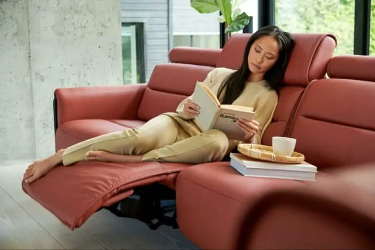 A woman reads while sitting on a Stressless sofa