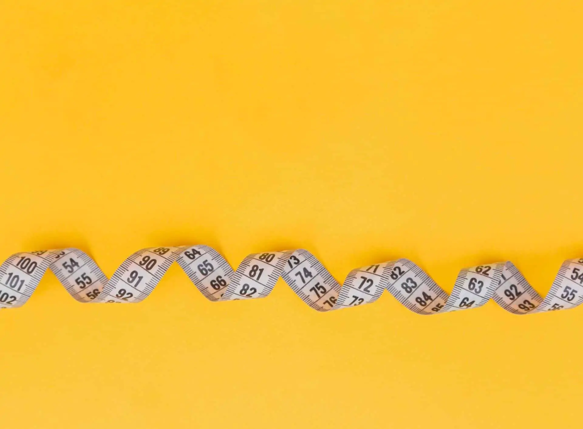 A measuring tape against a yellow background