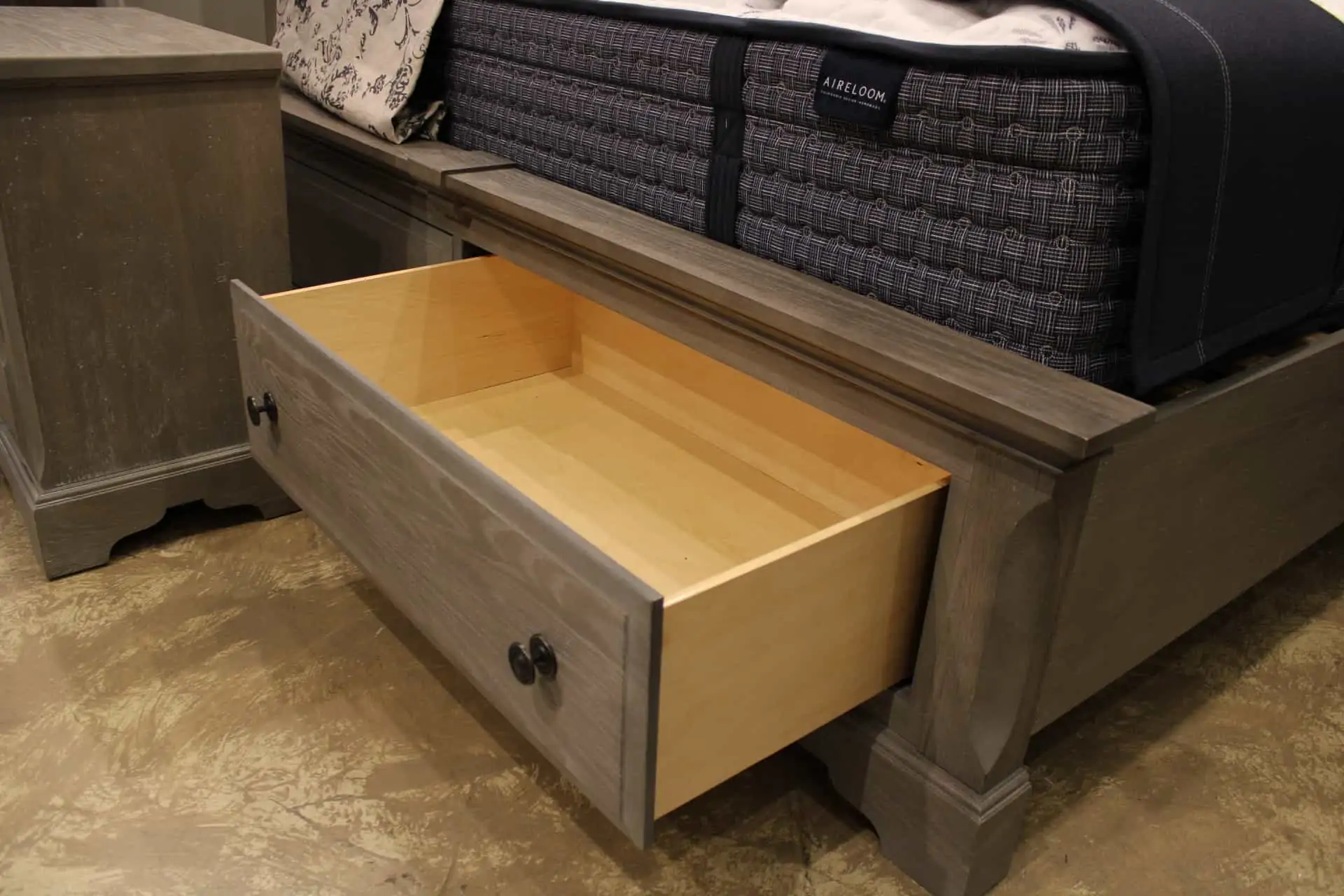 A bed frame with an opened drawer 